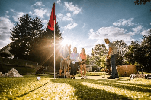 Bild einer Familie beim Minigolfspielen