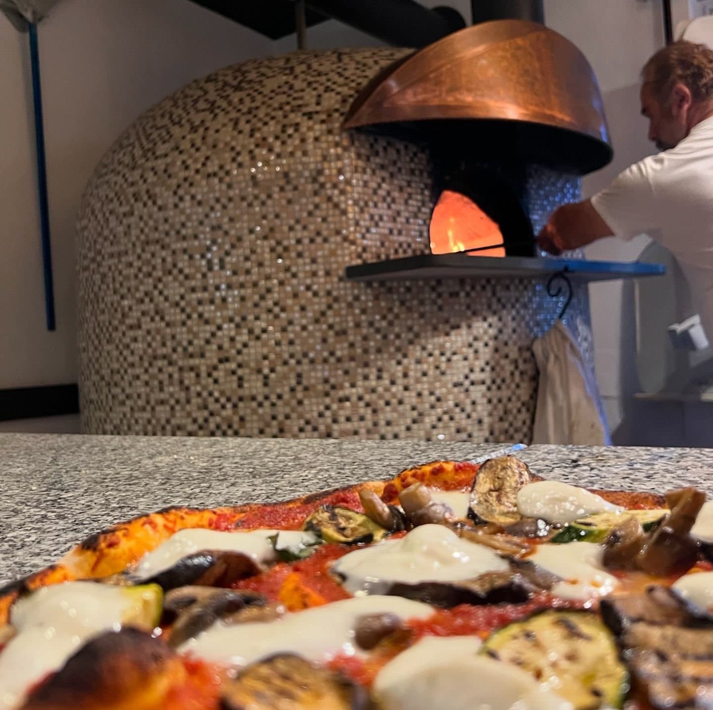 Steinofen mit leckerer Pizza im Vordergrund
