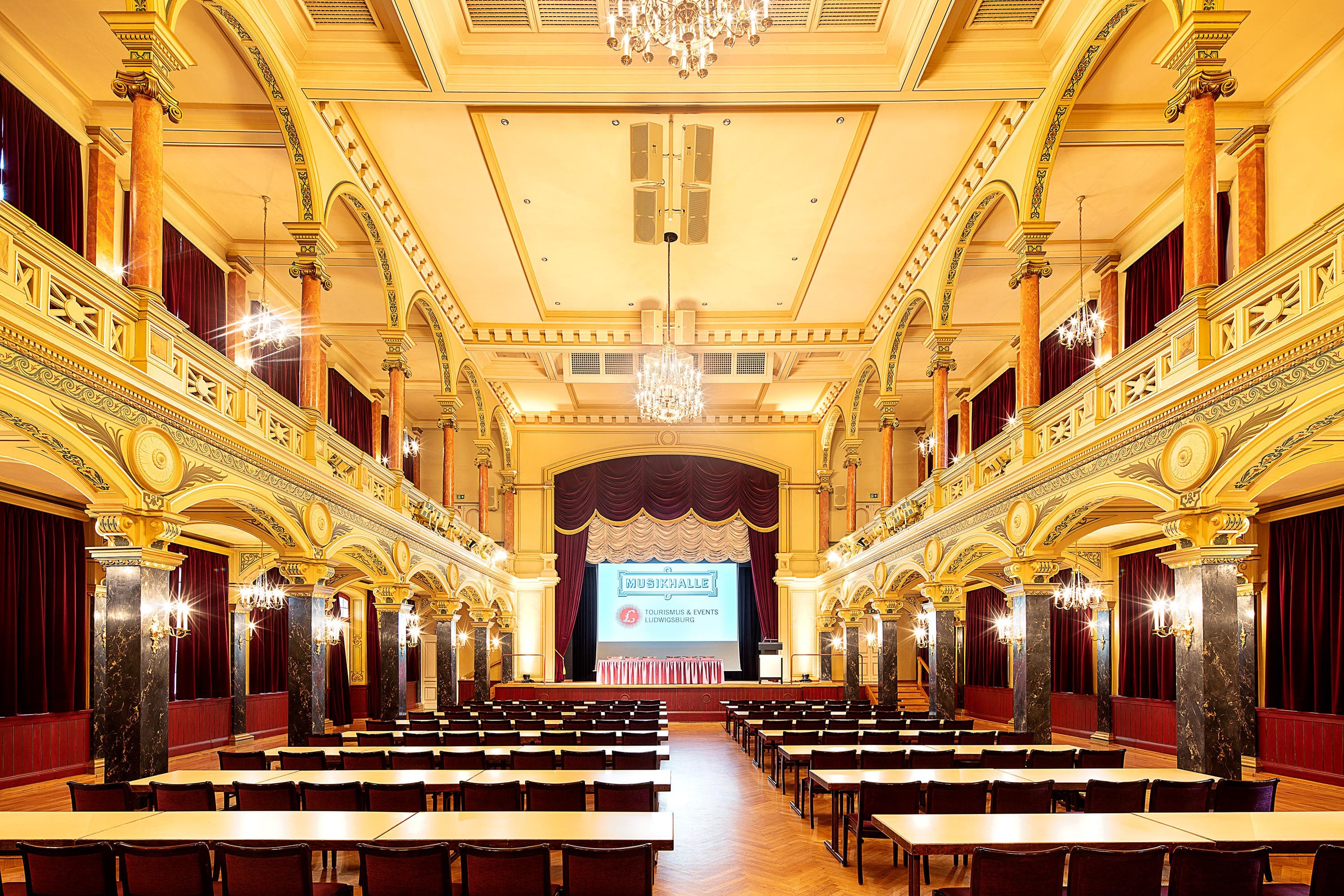 Innenansicht der Musikhalle Ludwigsburg mit prunkvollen Verzierungen und Kronleuchtern.