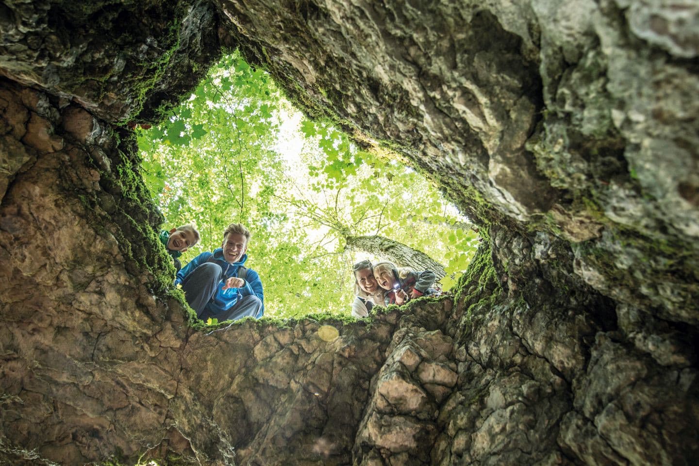 Vierköpfige Familie schaut durch ein Felsloch in die Tiefe