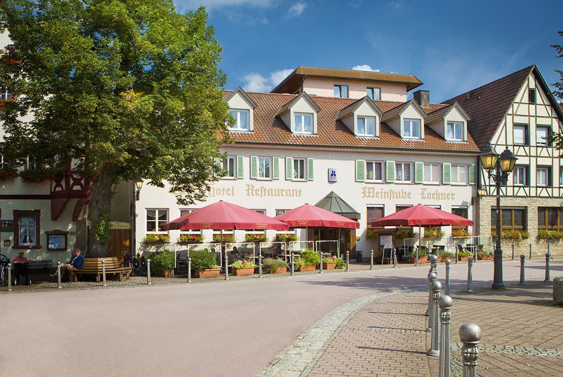 Frontansicht des Hotels vom Marktplatz aus. Vor dem Hotel sind Sonnenschirme aufgestellt.