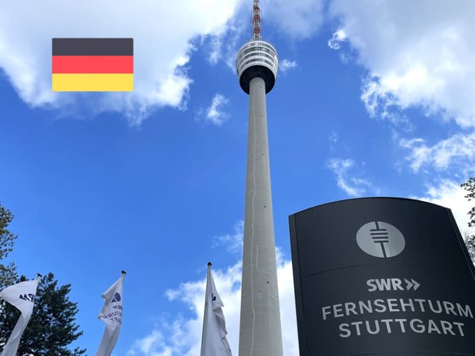 Fernsehturm Stuttgart mit blauem Himmel und deutscher Flagge.