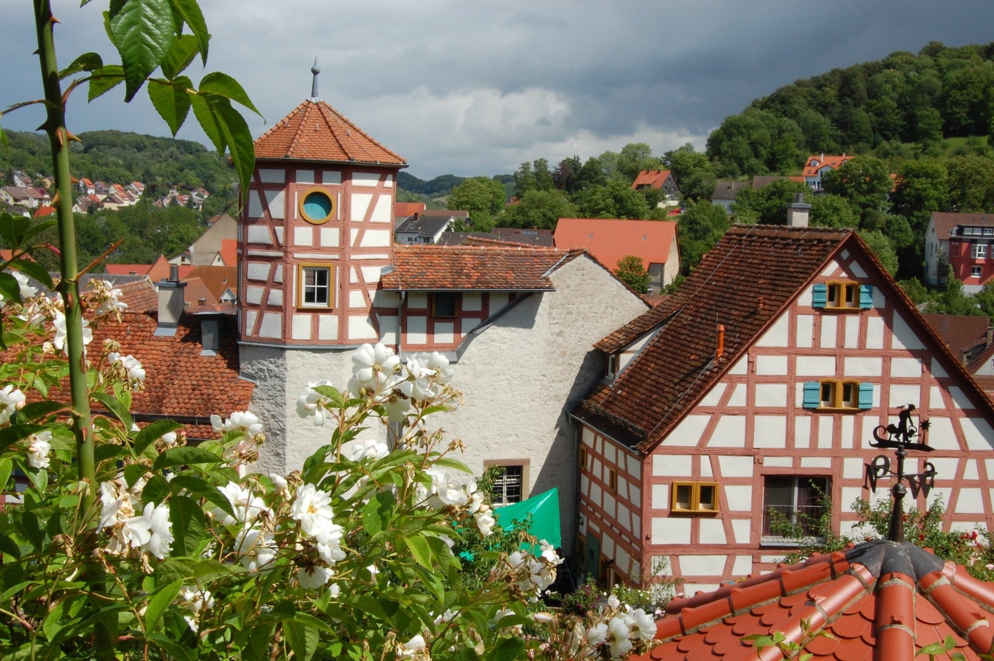 Blick auf das im Fachwerkstil errichtete Romschlössle. Im Vordergrund sind Rosen des dazugehörigen Rosengartens zu sehen.
