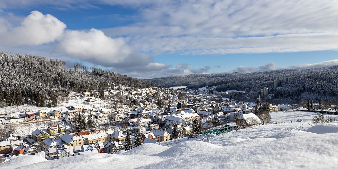 Weitblick über Furtwangen im Winter umgeben von schneebedeckten Wäldern