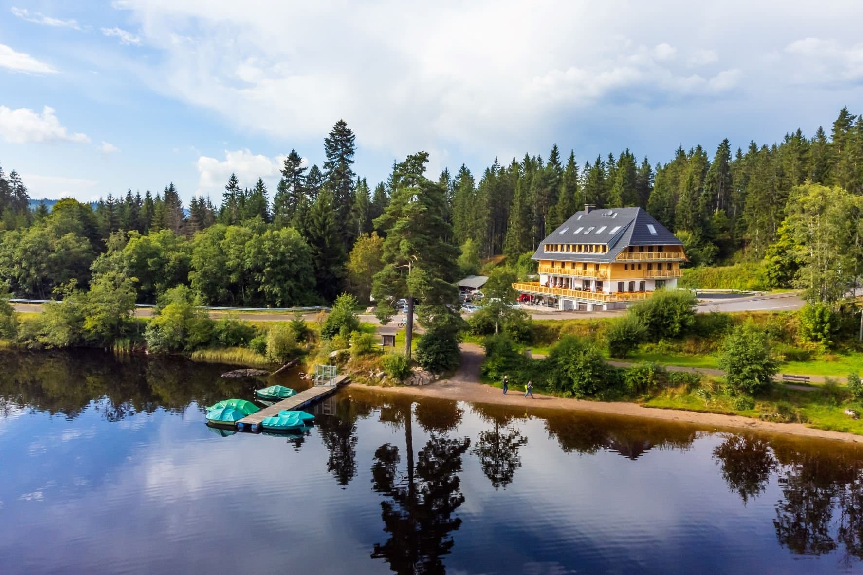 Ein ruhiger See mit Booten und einem großen Haus im Hintergrund.