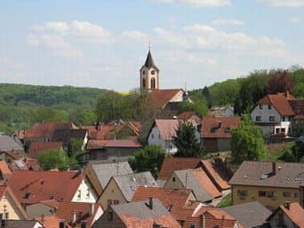 Blick auf eine Kirche auf einer Anhöhe und Häuserdächer
