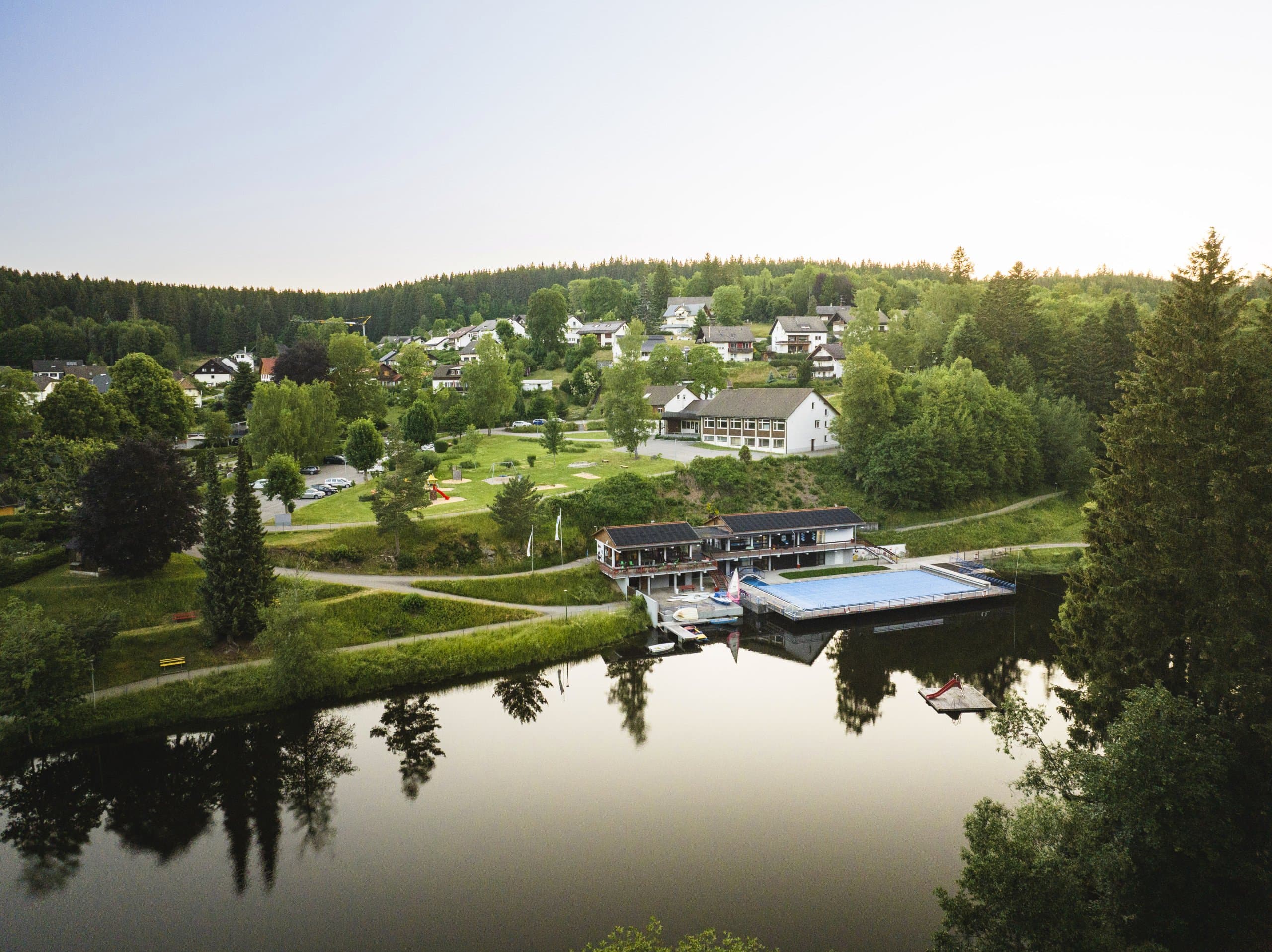 Freibad umgeben von  Wiesen, Bäumen und dem Klosterweiher in Friedenweiler