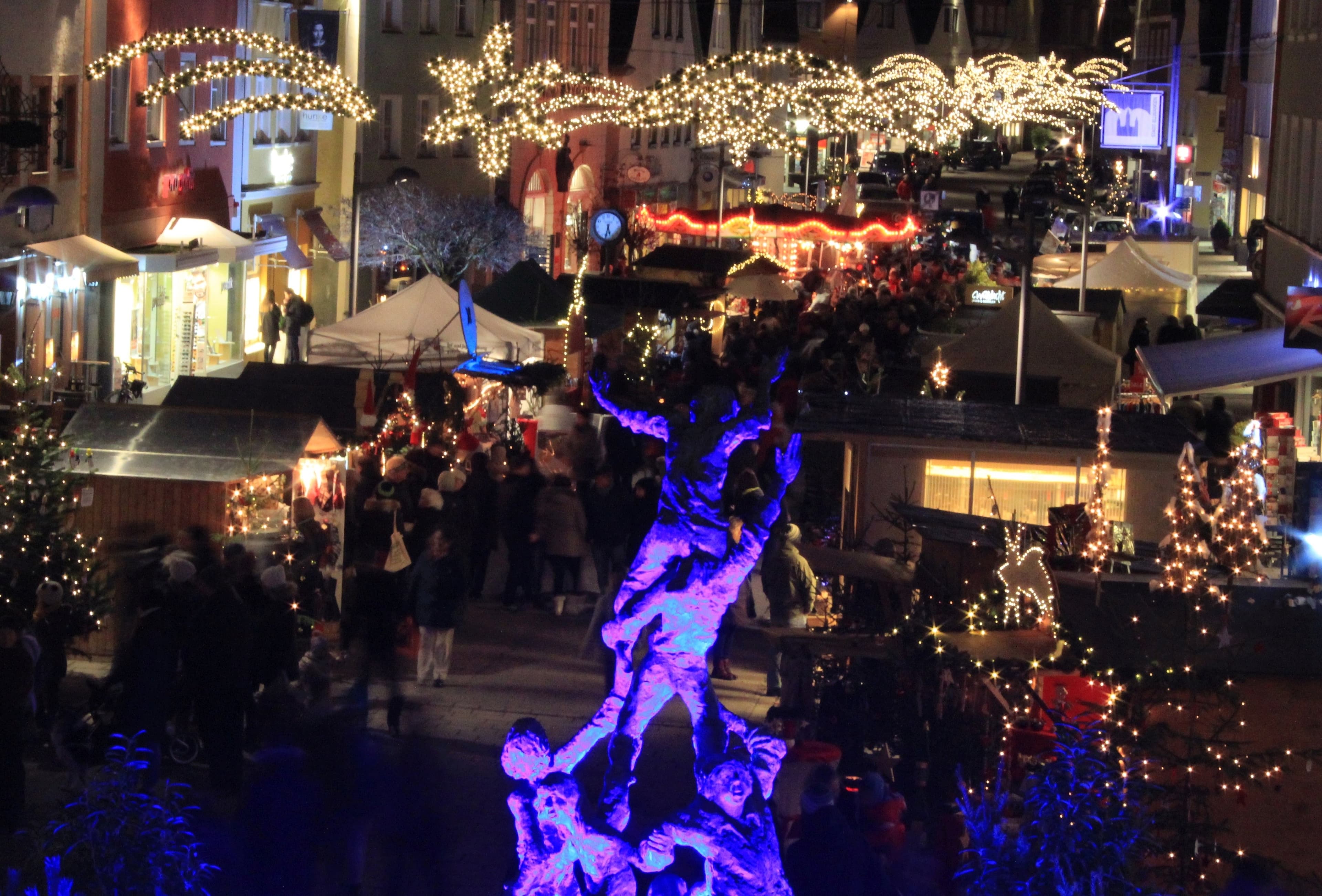 Weihnachtsmarkt bei Nacht mit Lichterketten und Ständen.