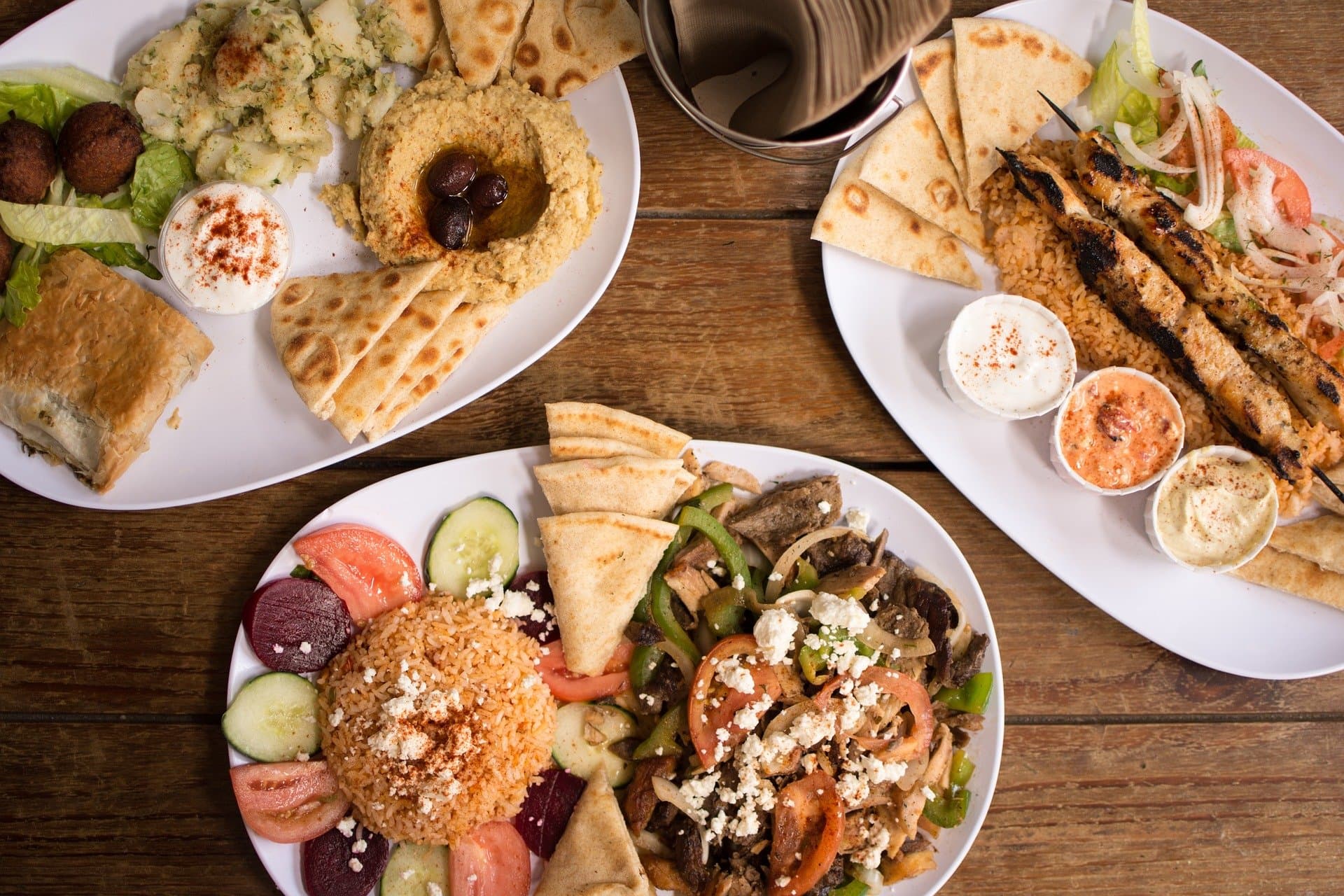 Several plates with Greek specialties such as souvlaki and pita bread