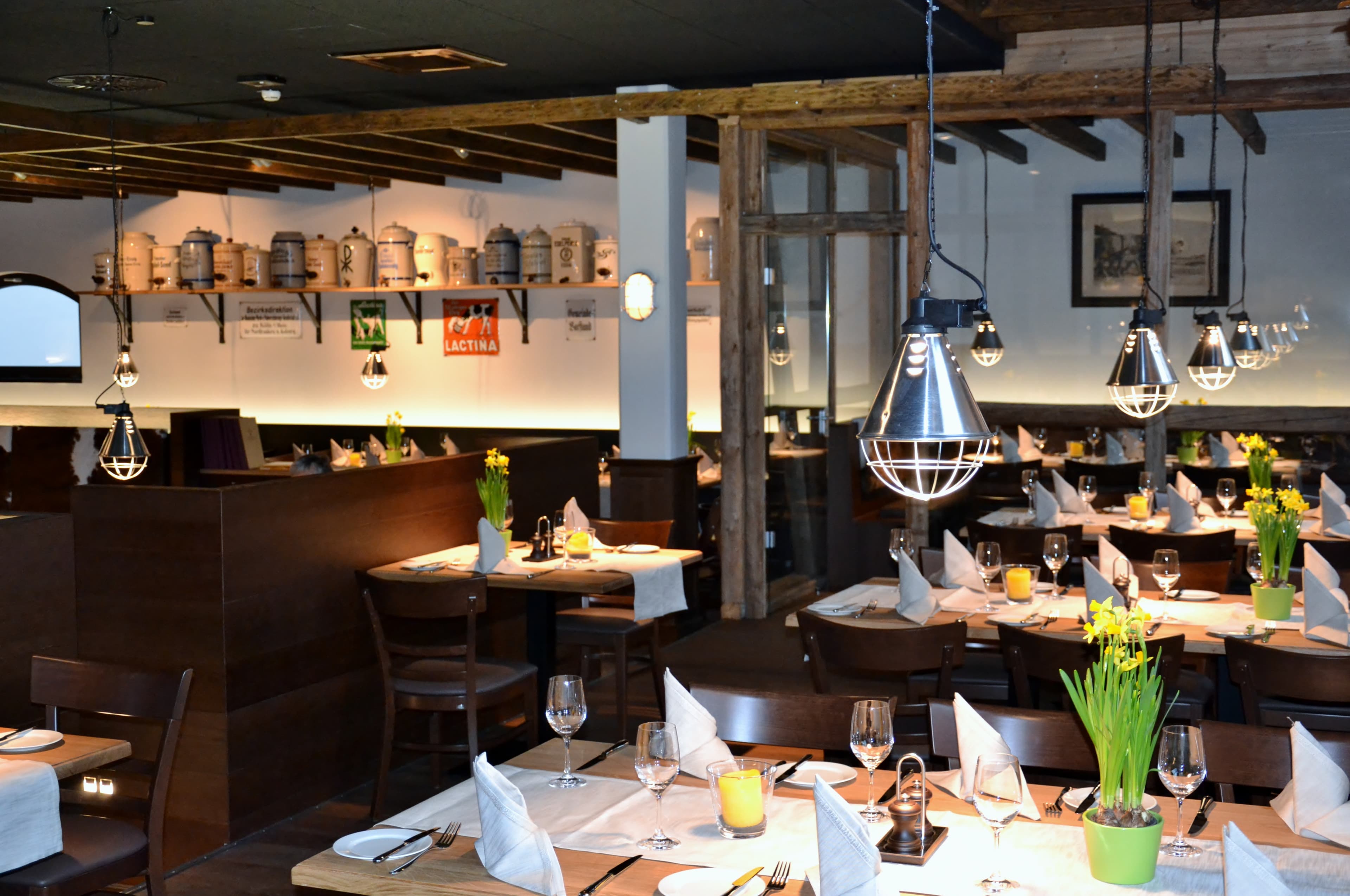 Der Gastraum im Jägerhof Restaurant. Auf dem Tisch stehen gelbe Narzissen. Im Hintergrund sind an der Wand verschiedene Keramikgefässe ausgestellt.