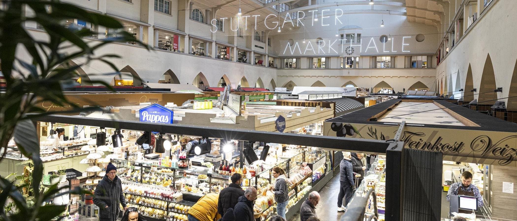 Innenansicht der Stuttgarter Markthalle mit Ständen und Besuchern.