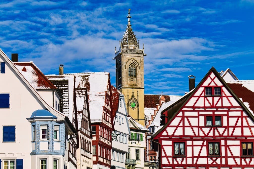 Fachwerkhäuser und Kirchturm mit Schnee bedeckt.