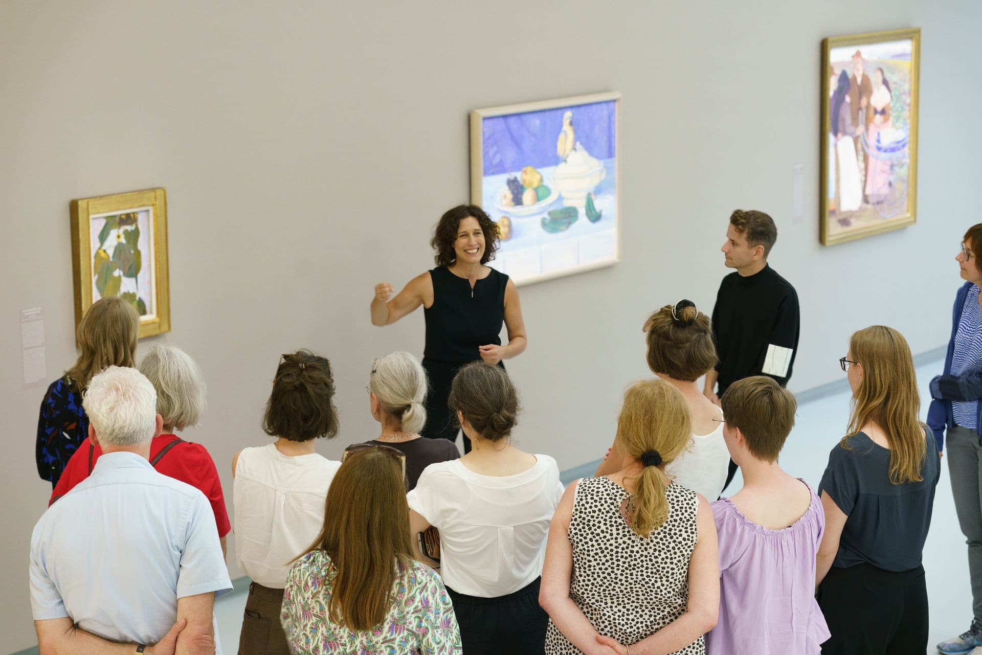 Die Direktorin der Kunsthalle erläutert einer Gruppe von Zuhörern die Bilder an der Wand.