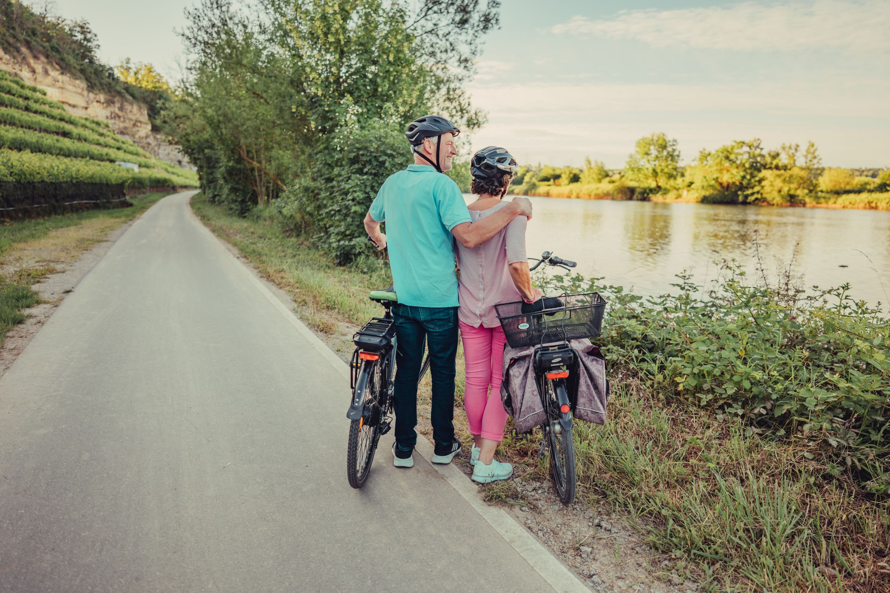 Ein Mann und eine Frau mit Fahrrädern stehen am Fluss.