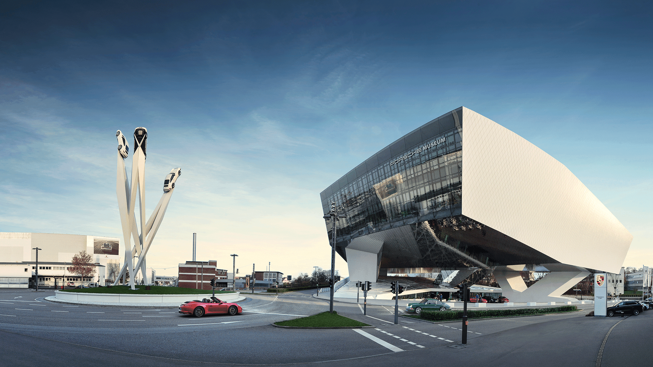 Das Porsche Museum in Stuttgart mit moderner Architektur und einer Skulptur von drei Autos auf hohen Säulen.
