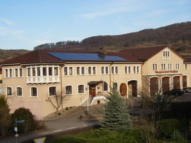 Winzergenossenschaft von außen, braunen Haus mit Wald im Hintergrund