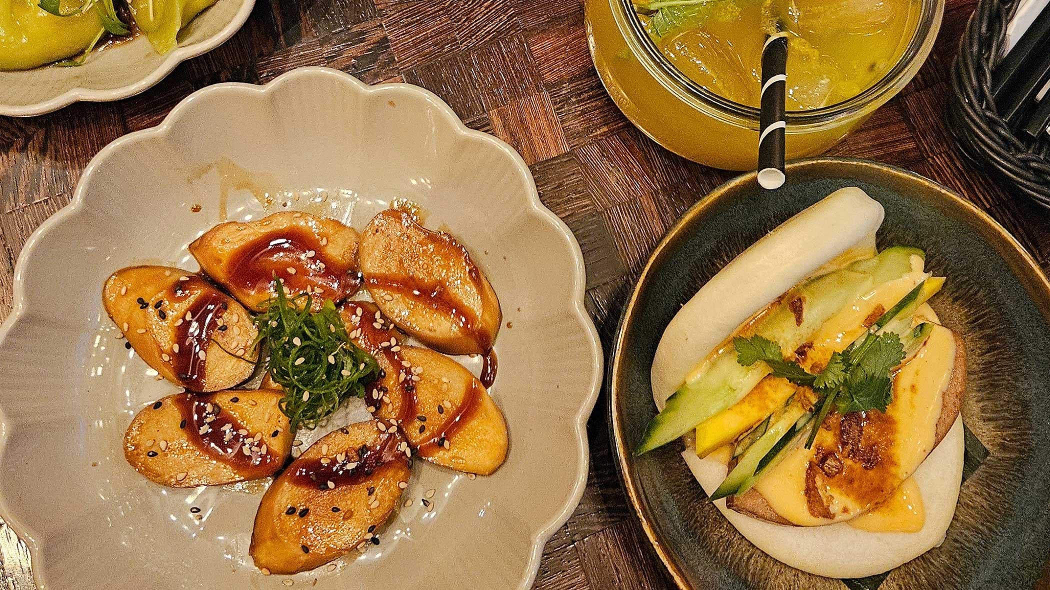 Veganer Teller mit Teigtaschen, Bao Bun und Getränk.