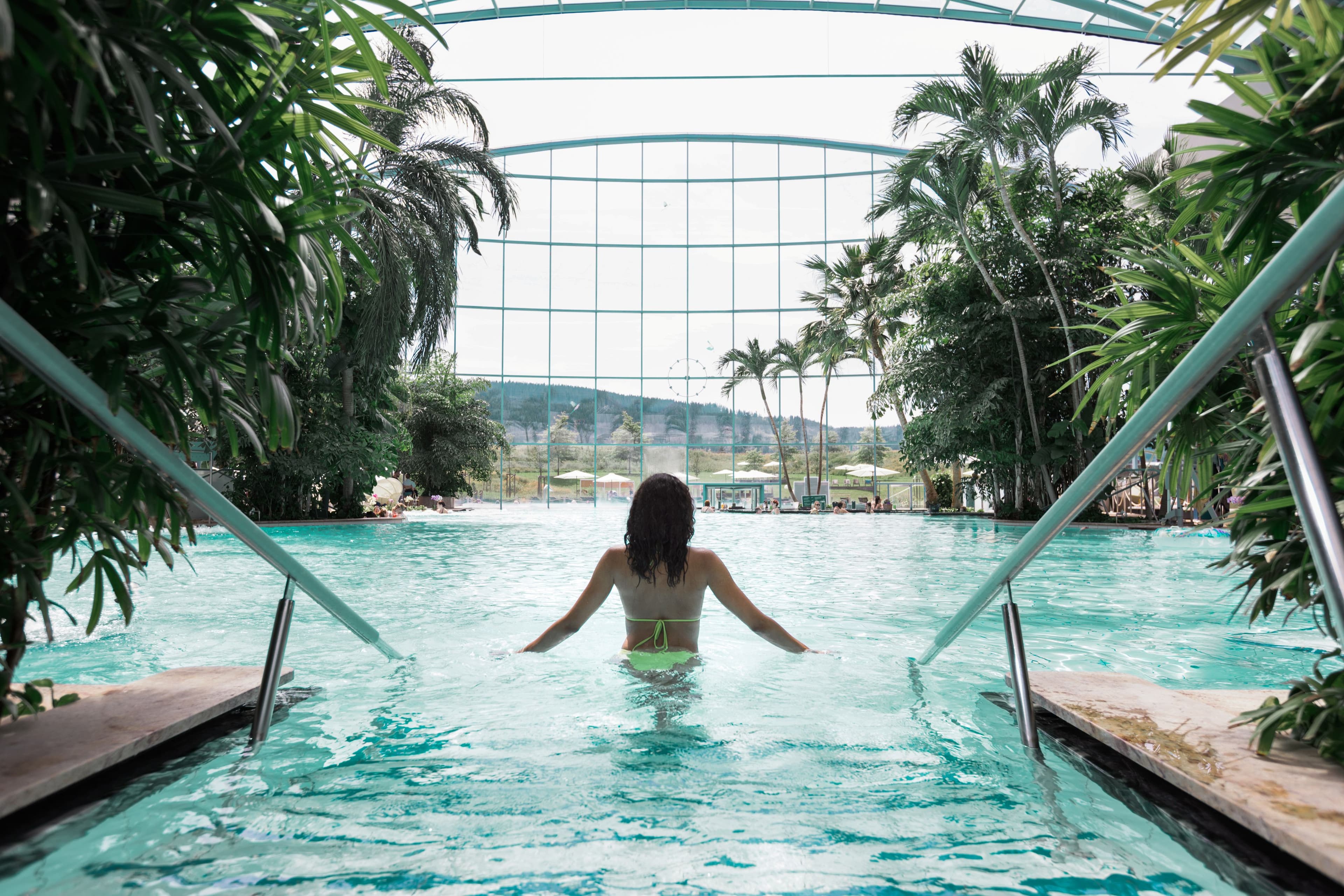 Eine Frau tritt in das türkisblaue Wasser der Blauen Lagune in der Palmenoase ein.