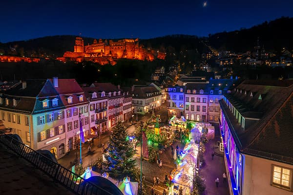 Colourful Christmas lights in an old town with illuminated houses and a Christmas tree.