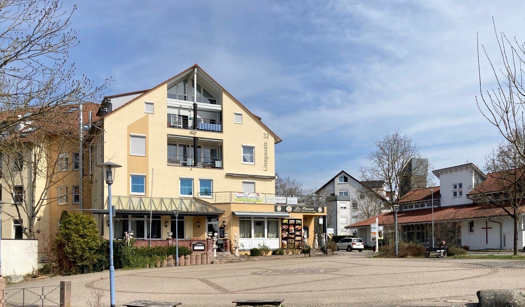 Zweistöckiges gelbes Gebäude mit Pizzeria im Erdgeschoss am Marktplatz in Oberuhldingen.
