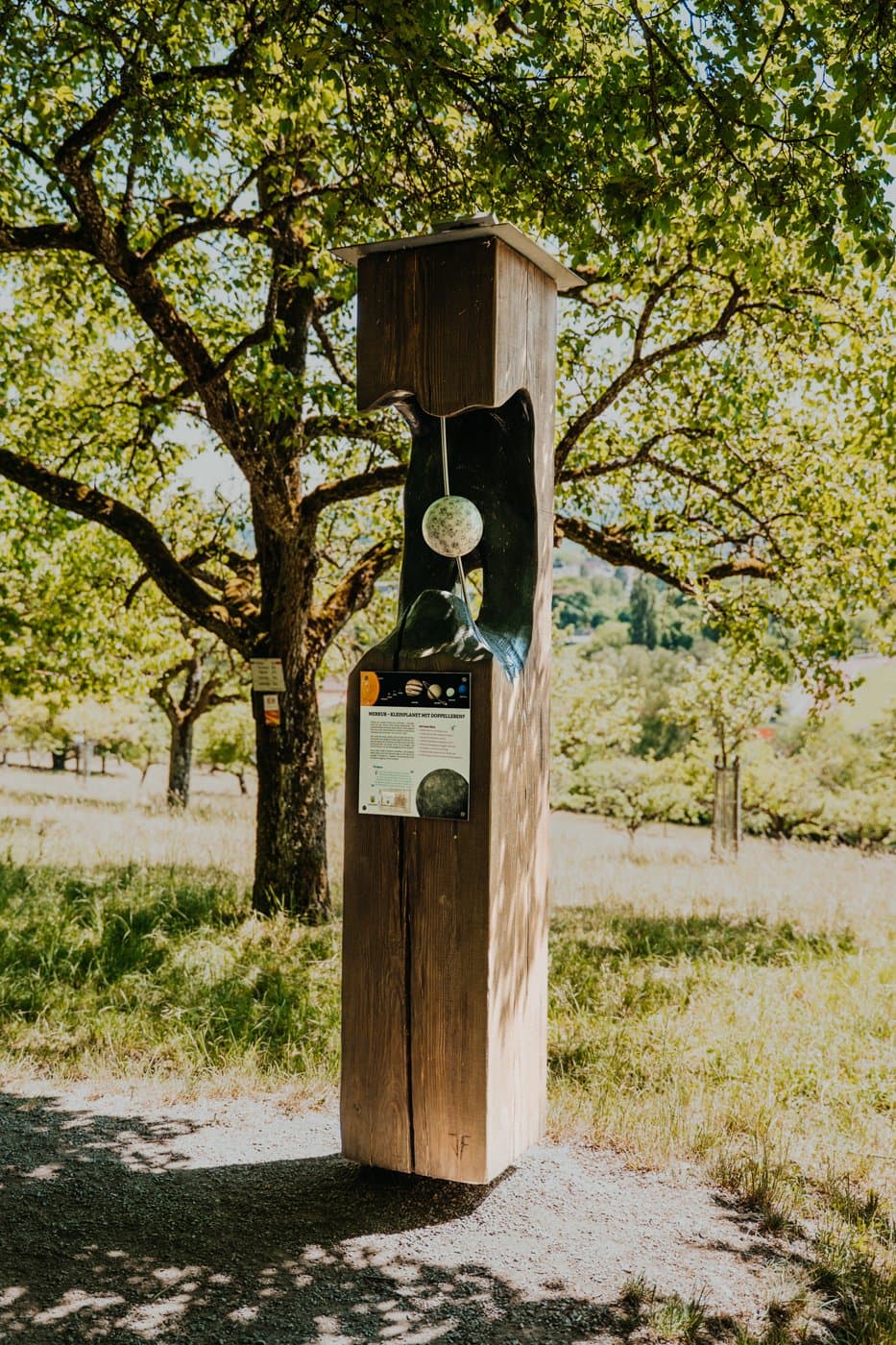 Zu sehen ist eine Stele, die im Grünen steht