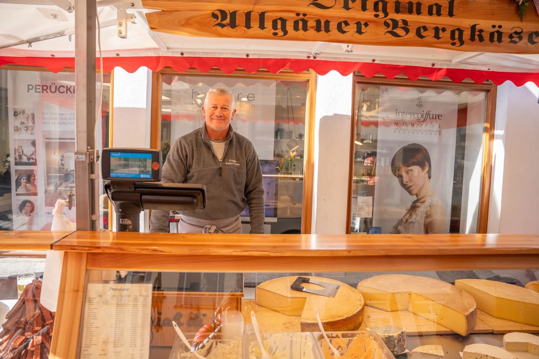 Ein Verkäufer in seinem Marktstand mit Käse auf dem Ravensburger Wochenmarkt.