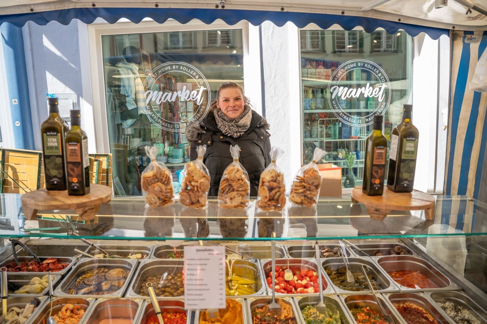 Eine Verkäuferin in Ihrem Stand mit Feinkost auf dem Ravensburger Wochenmarkt.