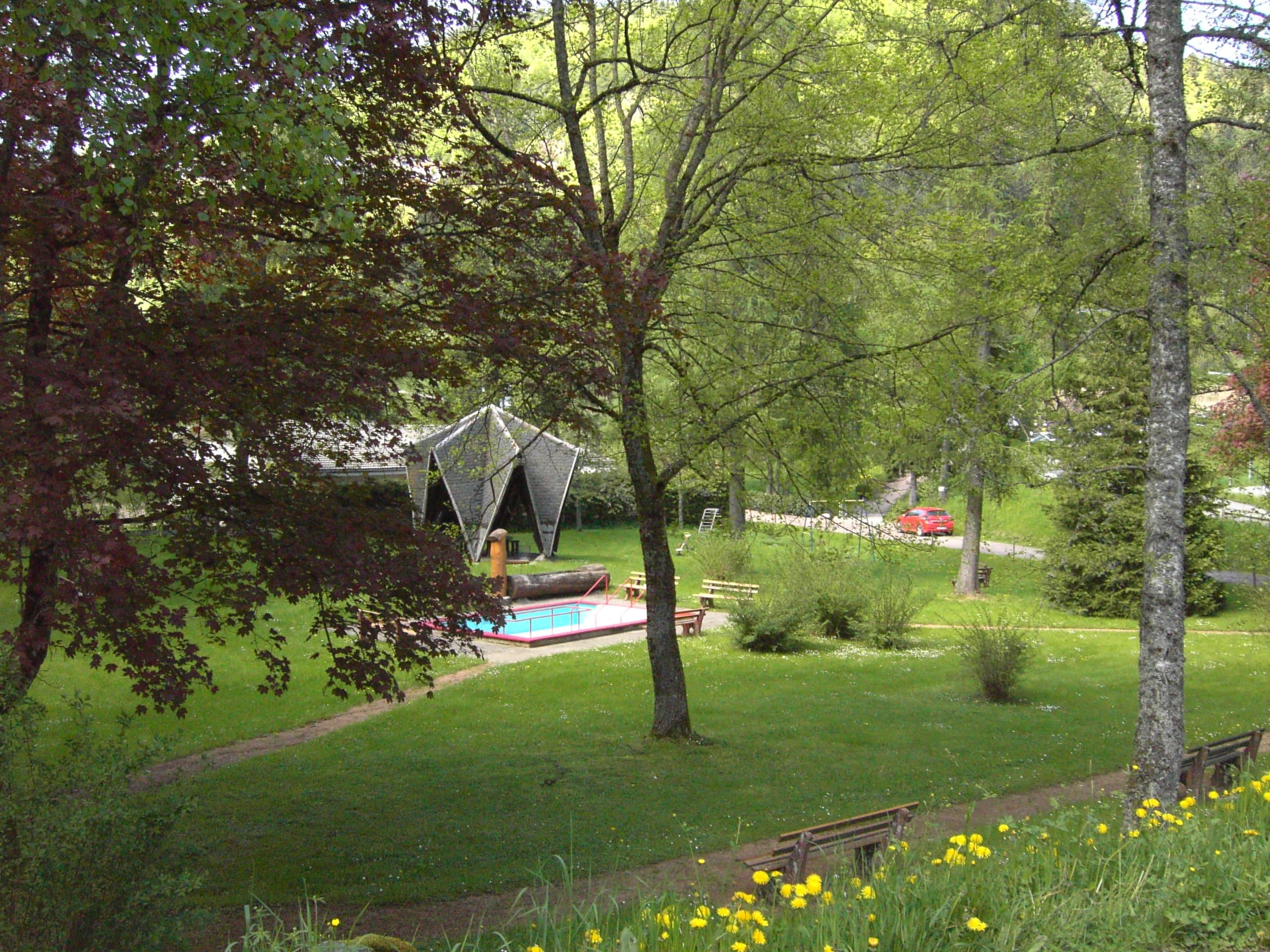 The water treading area is surrounded by green meadows and large trees such as birches and willows.  Behind the Kneipp pool is a wooden pavilion which serves as a shelter