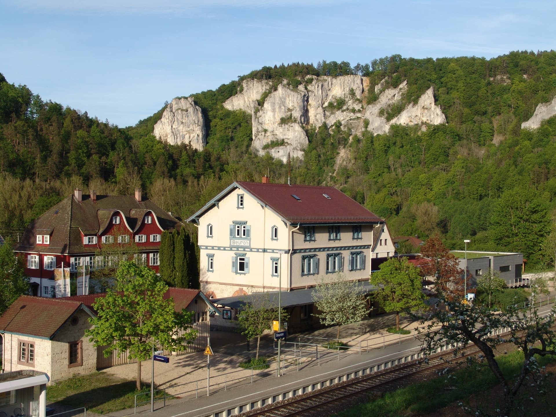 Historische Gebäude vor bewaldetem Hang mit massiven Kalkfelsen