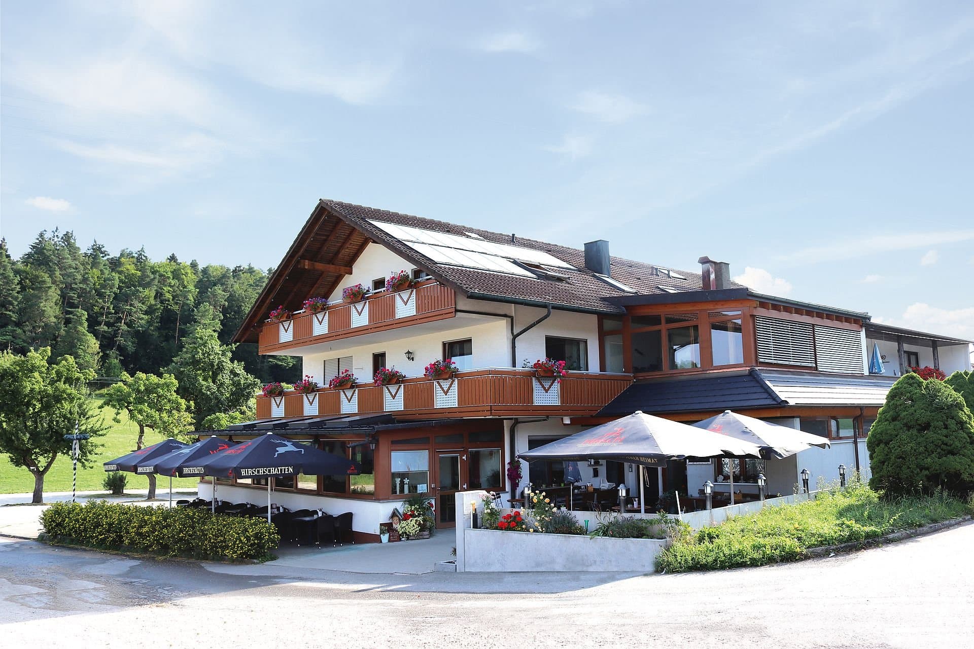 Außenansicht des Landgasthofes Waldeck auf dem Risiberg mit aufgespannten Sonnenschirmen auf der Terrasse