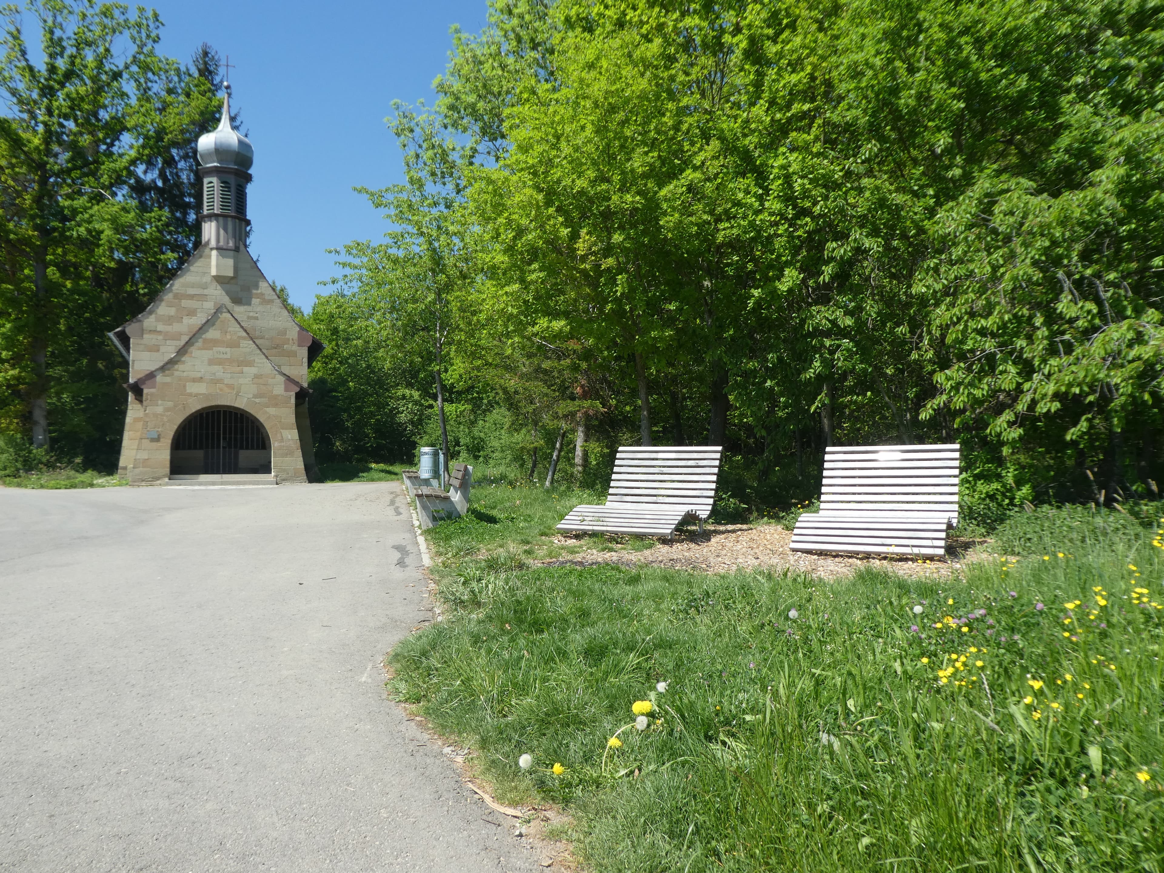 Eine kleine Kirche, davor Bänke.