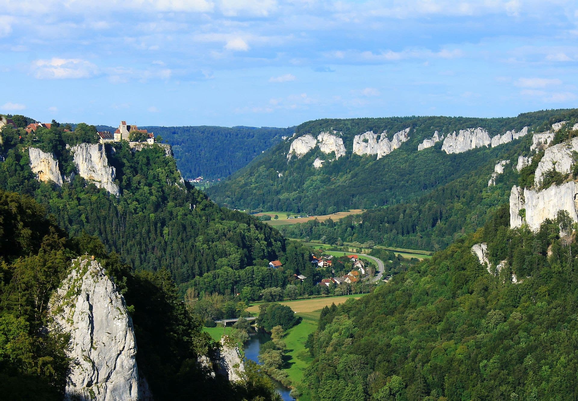Blick vom Eichfelsen hinunter auf das bewaldete und felsige Donautal und auf Schloss Werenwag, das auf einem Felsen thront